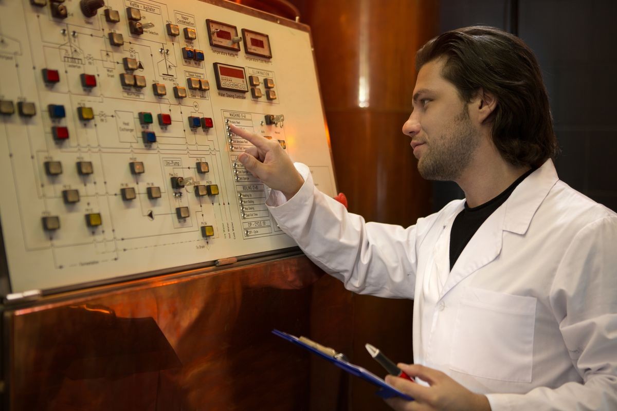 Chief engineer looking at control panel and pointing with finger on scheme. Worker of factory checking indexes and controlling manufacturing. Specialist holding folder and pen.